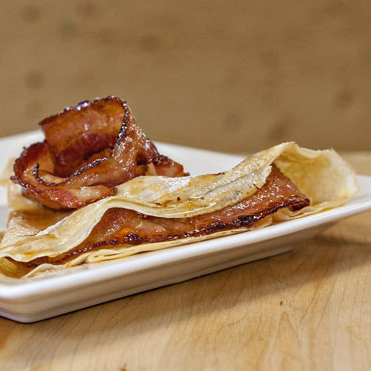 A crêpe filled with bacon and maple syrup, topped with whipped cream and more bacon.