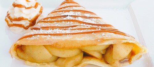 Crêpe filled with cinnamon and apples, topped with icing sugar, and homemade caramel.