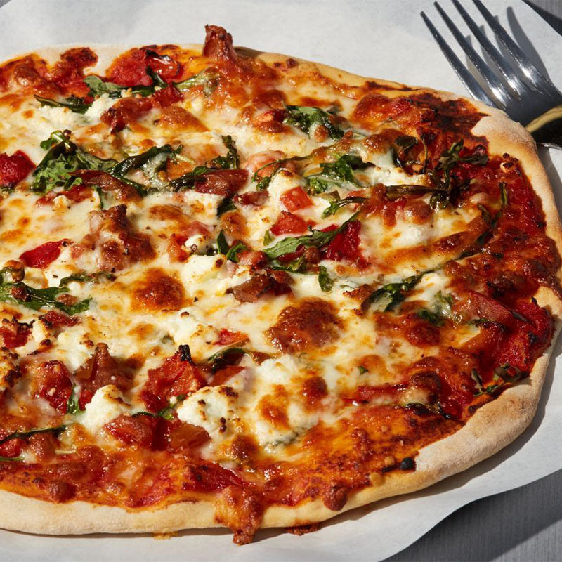 Pizza topped with roasted red peppers, basil, goat cheese and two-cheese blend, and a sprinkle of black pepper.