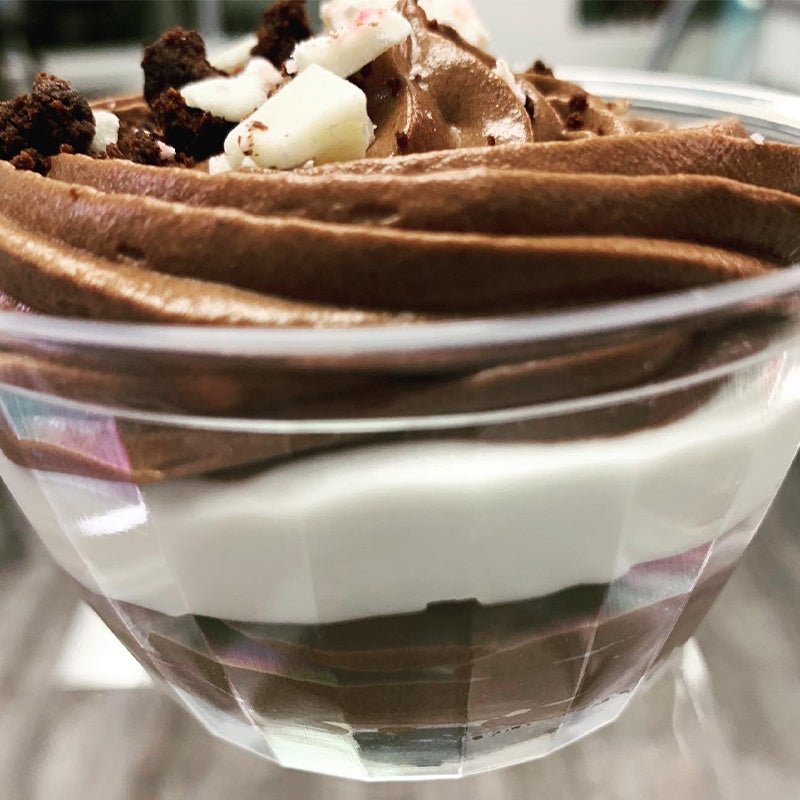 Glass bowl with chocolate mousse, layered with white chocolate mousse and brownie on the bottom.