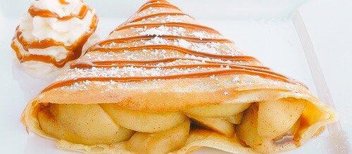 Crêpe filled with cinnamon and apples, topped with icing sugar, and homemade caramel.