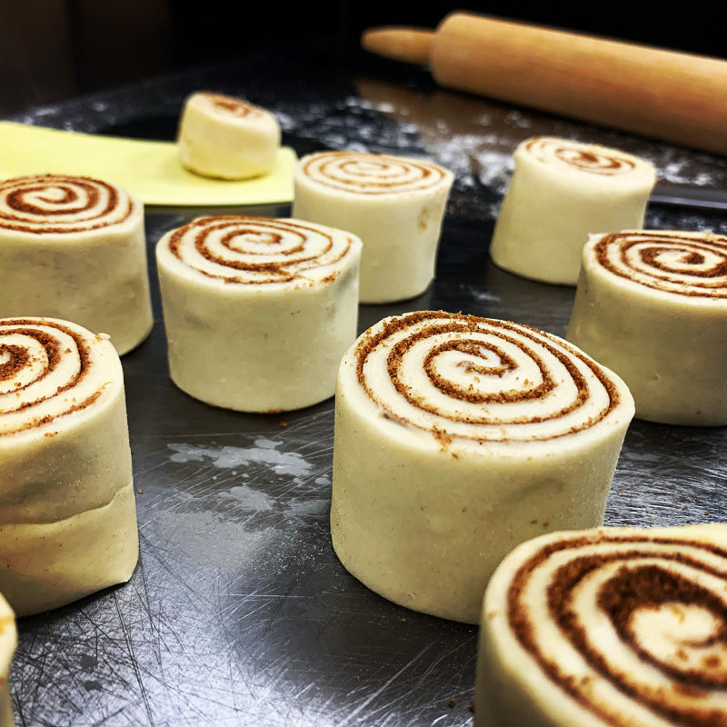 Uncooked puff pastry cinnamon rolls on table.