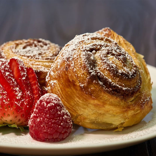 Homemade made-from-scratch puff pastry cinnamon sugar rolls with fresh fruit.