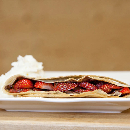 Crêpe filled with Nutella and sliced strawberries, topped with whipped cream.