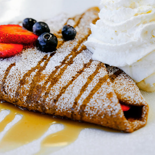 A lactose-free vegan crêpe filled with blueberries, strawberries, maple syrup, and vegan whipped cream.